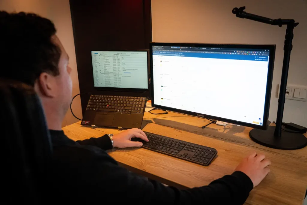 Tom werkt aan een website achter twee schermen