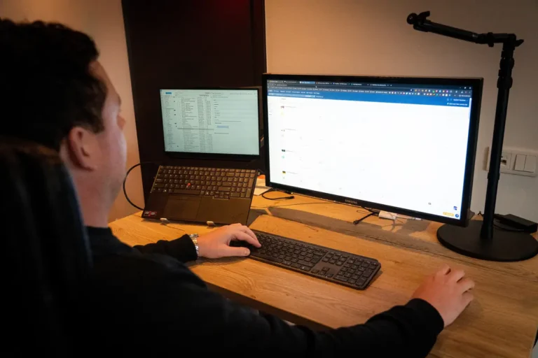 Tom werkt aan een website achter twee schermen